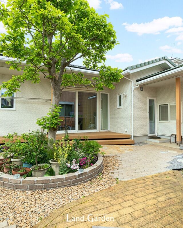 【緑豊かなつながりのある新築外構】

木の温もりを感じる平屋の新築外構プラン。
建物と調和する植物が良く似合うナチュラルなデザイン。

お庭はご家族が暮らす隣の建物とつながりのある空間にできました。大切にされている樹木を中心に花壇をつくり、植物に囲まれながらご家族皆さんで過ごせるようなデザインとなっています。ウッドデッキは軒下を最大限利用できるように設置したため、腰掛けながら植物を眺めていただけます。

ファサードは塗り壁と木目を多く採用し柔らかい雰囲気になりました。

【使用建材】
■ウッドデッキ：樹ら楽ステージ（LIXIL）
■レンガ：シャルドブリックペイブ（TOYO）
■乱形石：オークルストーン（TOYO）

https://www.land-garden.net/
🌿内と外が調和する庭づくり🌿
------------------------------------------
《ランド・ガーデン千葉》
🌱 千葉県四街道市もねの里1-2-18
TEL.043-420-2000
⁡
《ランド・ガーデン八千代》
🌱 千葉県八千代市大和田新田103-34
TEL.047-450-0100

営業時間 9:00 ～ 17:00 （水曜定休）

《施工エリア》
千葉市(若葉区は一部除外・緑区はエリア外)・船橋市・習志野市・八千代市・佐倉市・四街道市・白井市・印西市・酒々井町・富里市・八街市・成田市の一部
------------------------------------------⁡
▽ 施行事例
https://www.land-garden.net/works/

▽お客様の声
https://www.land-garden.net/voice/

#外構 
#エクステリア 
#ウッドデッキのある暮らし 
#新築外構 
#平屋暮らし 
#白井外構 
#LIXIL 
#樹ら樂ステージ 
#ガーデンライフ 
#庭づくり 
#おしゃれな外構 
#外構デザイン 
#ナチュラル外構 
#塗り壁のある暮らし 
#シンボルツリーのある庭 
#花壇づくり